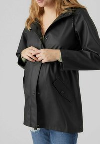 Zwarte, waterdichte jas met een capuchon, ritsluiting, drukknoopjes en zijzakken. Gladde textuur, iets loose fit, geschikt voor het dragen in lagen.