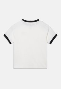 T-shirt branca de algodão com gola e bordos das mangas pretos canelados. Mangas raglan curtas e textura limpa e suave. Sem gráficos visíveis.