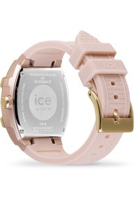 Montre avec bracelet en silicone rose, boîtier carré en acier inoxydable, accents en or rose et bande texturée. Résistante à l'eau jusqu'à 5 ATM.