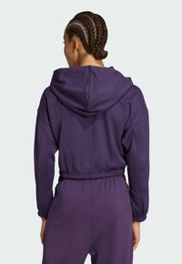 Sudadera con capucha morada de tejido texturizado, con capucha de gran tamaño y cintura elástica. Cuenta con mangas largas y un corte holgado.