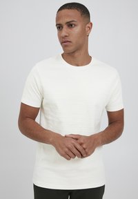 Hvid kortærmet t-shirt med vandret ribbet tekstur. Rund halsudskæring. Glat stof med minimalistisk udseende.