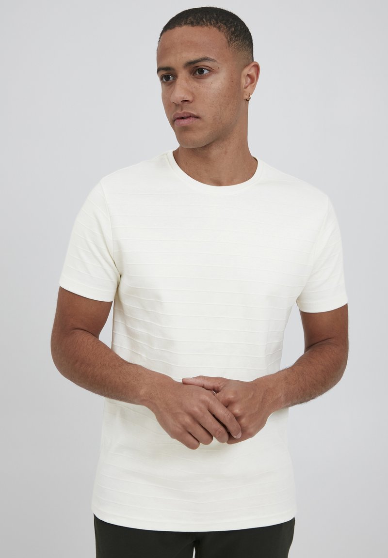 Hvid kortærmet t-shirt med vandret ribbet tekstur. Rund halsudskæring. Glat stof med minimalistisk udseende.