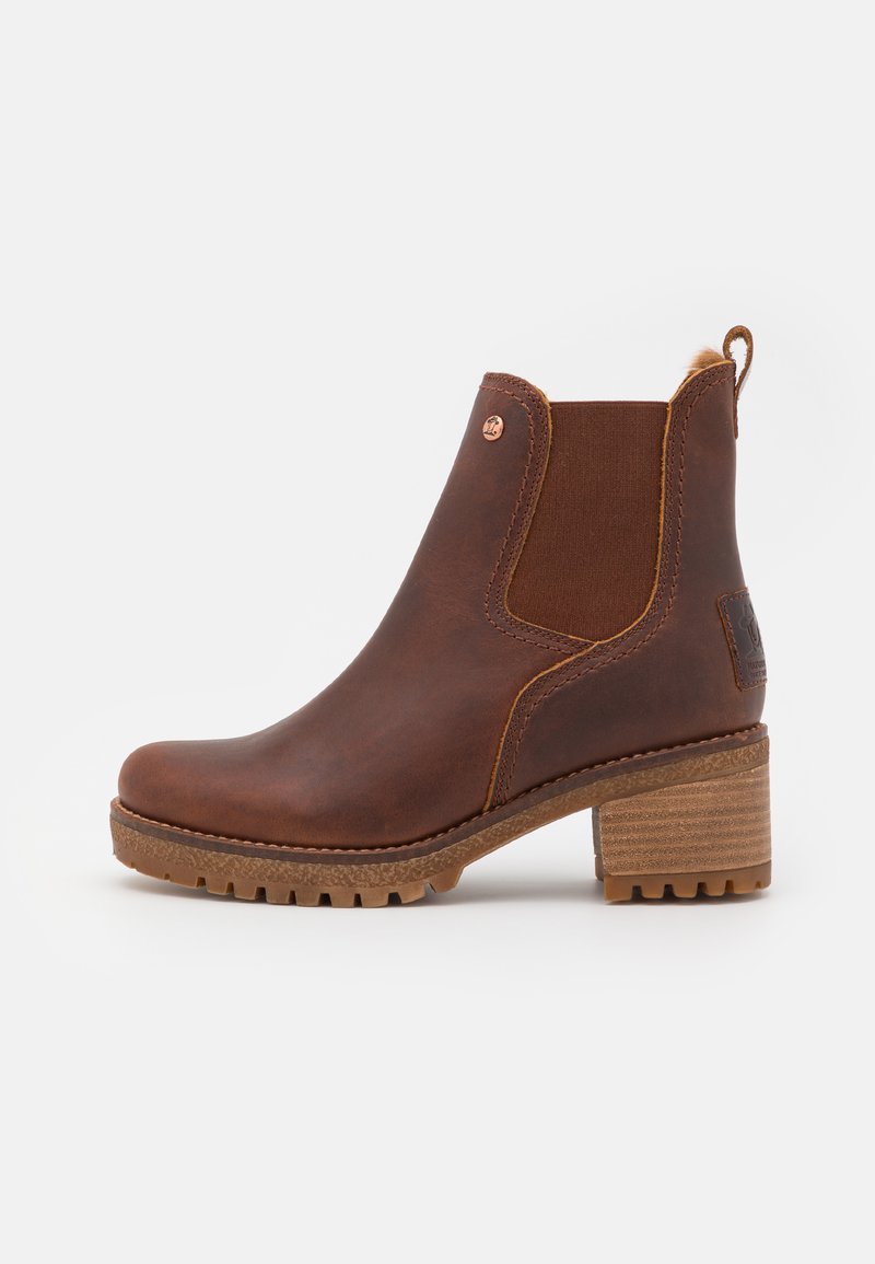 Καφέ δερμάτινη μπότα μέχρι τον αστράγαλο με ελαστι�κές πλαϊνές πάνελ, υφή από καουτσούκ για την σόλα και με στοίβαγμα στη φτέρνα. Διαθέτει διακοσμητικό λογότυπο στην φτέρνα.