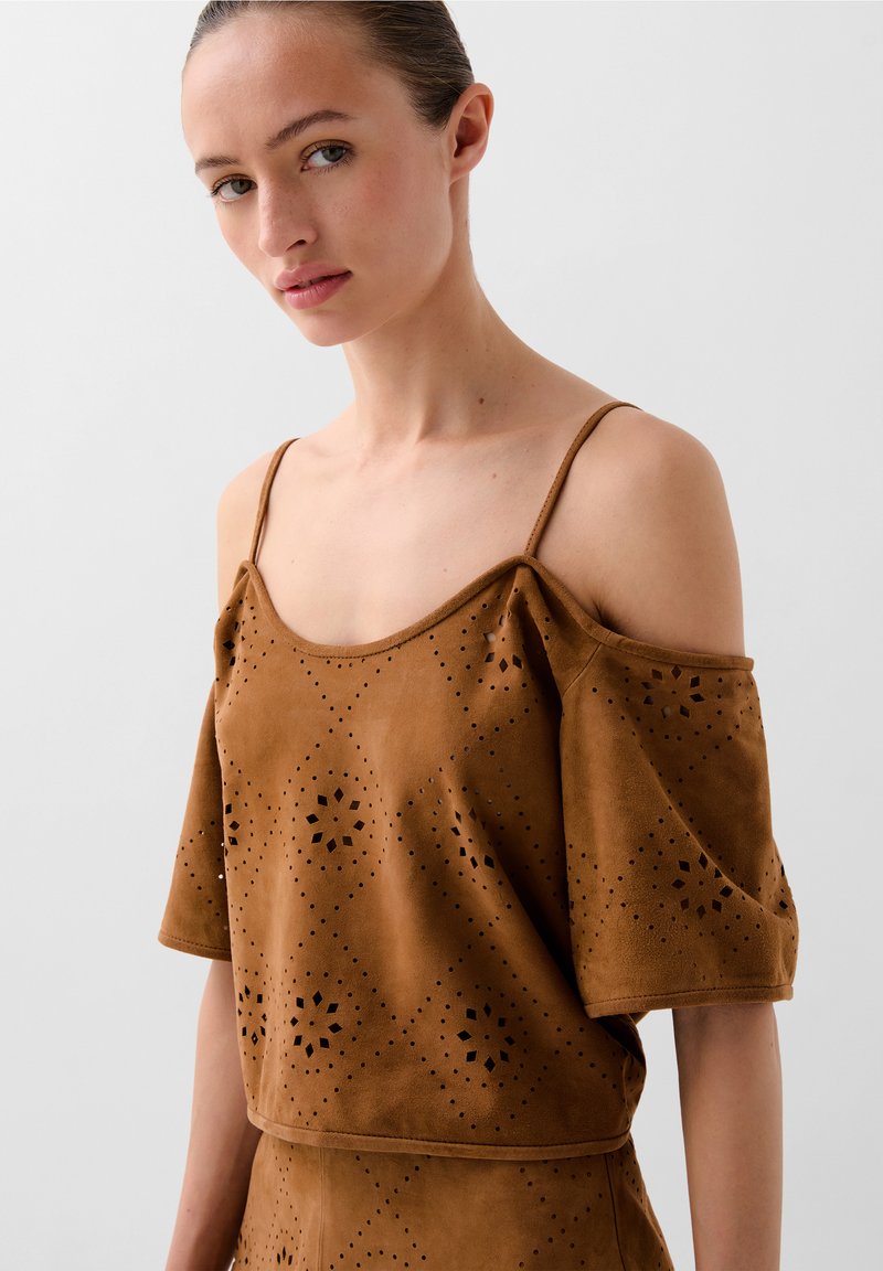 Brown, suede off-the-shoulder top with short sleeves, featuring perforated floral patterns and a relaxed fit design.