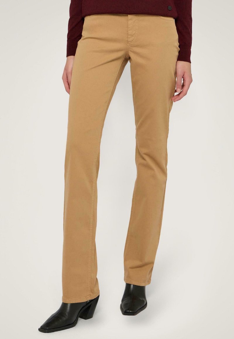 Pantalones de algodón beige con un diseño de pierna recta, textura suave y cintura de media altura, combinados con botines negros de tacón.
