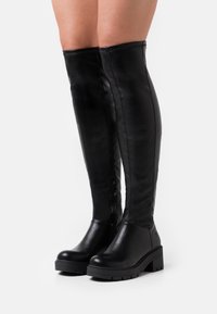 Botas de cuero negro hasta la rodilla con una textura suave, cremallera lateral y suela de plataforma negra gruesa. Diseño limpio con acentos mínimos.
