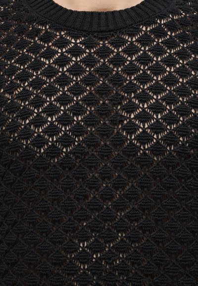 Μαύρο πλεκτό πουλόβερ με ανοιχτό μοτίβο ραφής σε σχήμα ρόμβου που αποκαλύπτει το δέρμα από κάτω, με ριμπ στρογγυλή λαιμόκοψη.
