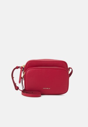 Červená kožená crossbody taška s dvěma zipovými přihrádkami, hladkým povrchem, zlatými kovovými detaily a odnímatelným popruhem.