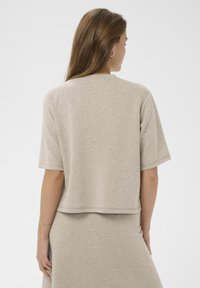 Īsām piedurknēm, beidzīga blūze no fakturēta auduma, ar brīvu piegriezumu un taisnu apakšmalu, apvienota ar atbilstošām svārkiem.