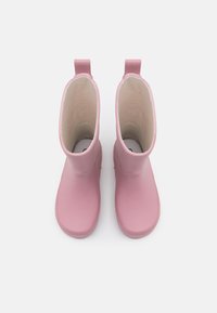 Bottes de pluie en caoutchouc roses avec une surface lisse, des orteils arrondis et des languettes pour un enfilage facile. L'intérieur est doublé d'un tissu beige doux.