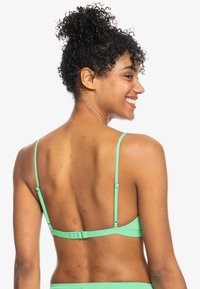 Mentolová podprsenka s nastavitelnými tenkými ramínky, zapínáním na háček a očko na zadní straně a hladkým, strukturovaným povrchem.