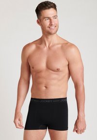Svarta boxertrosor för män med ett tjockt midjeband som har "JOCKEY"-logotypen. Tygmaterialet är mjukt och kroppsnära.