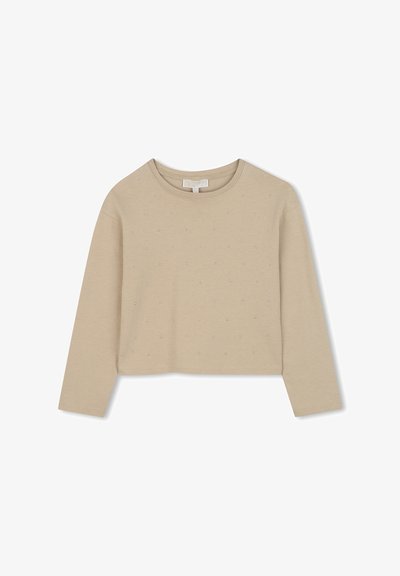 Κοντομάνικο μπεζ τοπ με μακριά μανίκια, που διαθέτει στρογγυλή λαιμόκοψη και διάσπαρτες ρινοστάτες στο μπροστινό μέρος. Μαλακό ύφασμα από μείγμα βαμβακιού.