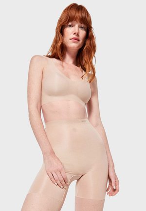 Soutien-gorge nude sans coutures et shorts taille haute en tissu extensible et lisse ; présente un design minimaliste et une marque discrète sur la ceinture.