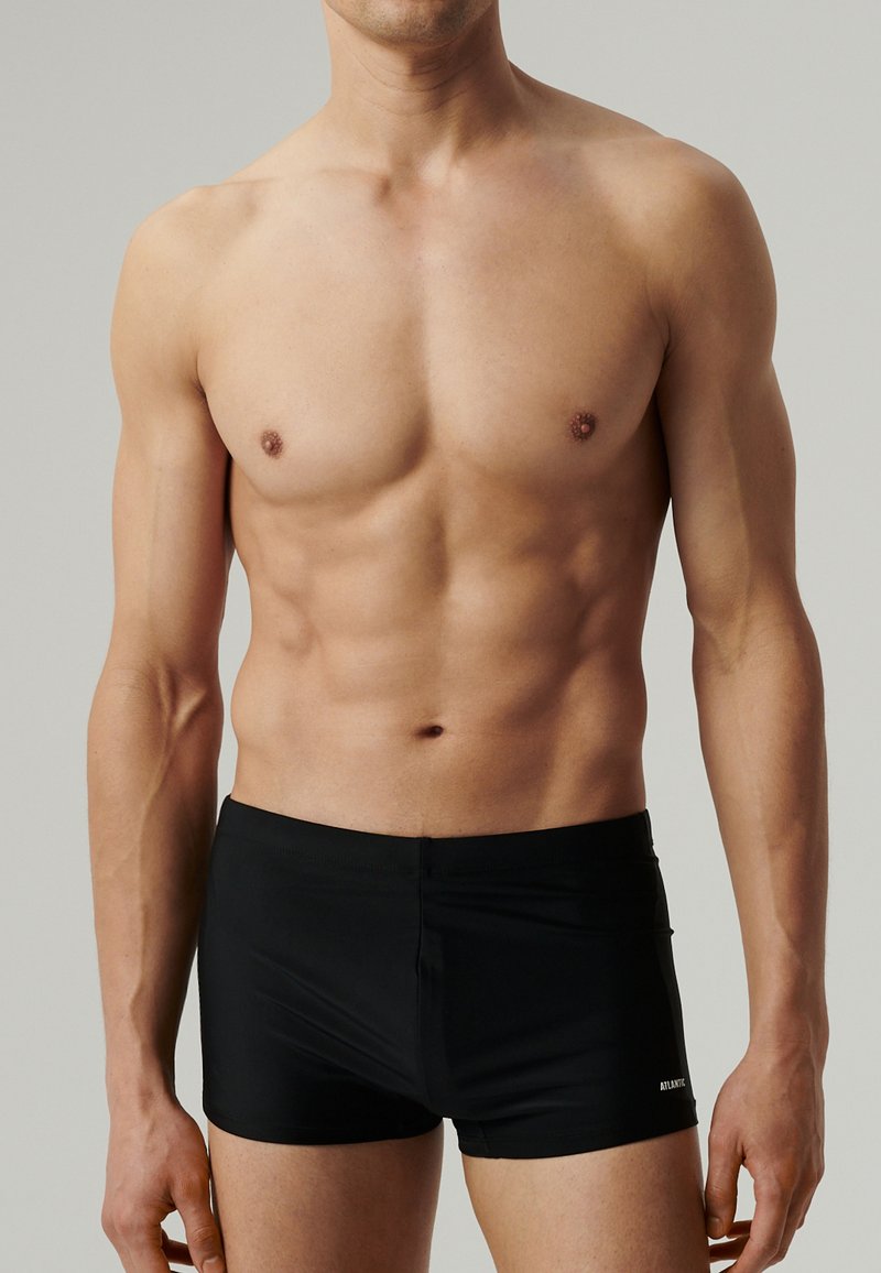 Czarne szorty do pływania wykonane z gładkiego, elastycznego materiału o dopasowanym kroju. Pas jest elastyczny, z małym logo z boku.