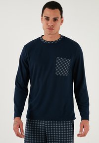 Tamno plava košulja dugih rukava s kariranom džepom i ovratnikom. Meki materijal, jednostavan dizajn i kontrastni uzorci.