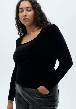 Black velvet long-sleeve top with a scoop neckline, paired with high-waisted black leather pants. Simple design and smooth texture.