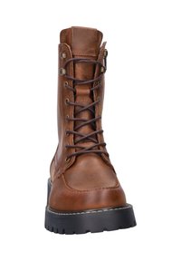 Bruine leren veterschoen met metalen oogjes, ronde neus en een robuuste zwarte zool. Kenmerkt zich door stikseldetails en een ritssluiting aan de zijkant.