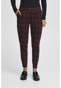 Tapered geruite broeken in bordeauxrood, groen en zwart met zijzakken en een gladde textuur, gecombineerd met glanzende zwarte loafers.