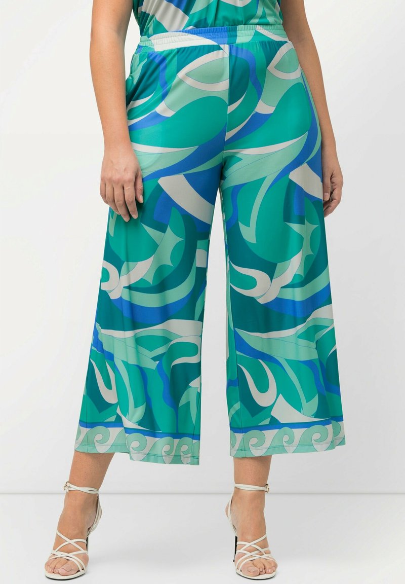 Pantalons cropped à jambes larges en motifs abstraits teal et bleu, fabriqués en tissu léger avec une taille élastique et une finition lisse.