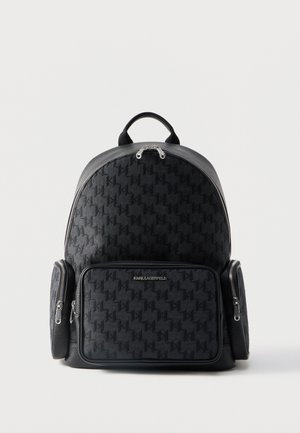 Must seljakott mustrilise kangaga, esiküljel ja külgedel lukuga taskud, ülalt käepide ja "Karl Lagerfeld" logo esimesel taskul.