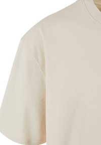 Beige bomulds t-shirt med rund halsudskæring og korte ærmer. Glat tekstur med en let tætsiddende pasform. Ingen mønstre eller udsmykninger.