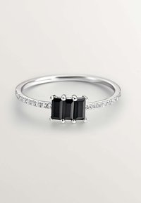 Anillo de plata con tres piedras preciosas rectangulares negras en un ajuste central, acentuado por pequeñas piedras claras a lo largo de la banda.
