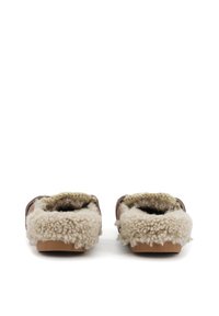 Zapatillas de cuero marrón con suave forro de borreguillo crema, sin parte trasera y suelas de goma tostada. La tela texturizada muestra detalles de lana natural.
