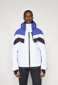 Biela a modrá lyžiarska bunda s čiernymi akcentmi. Má vysoký golier, nastaviteľnú kapucňu a zips vpredu. Materiál pôsobí vodoodpudivo.