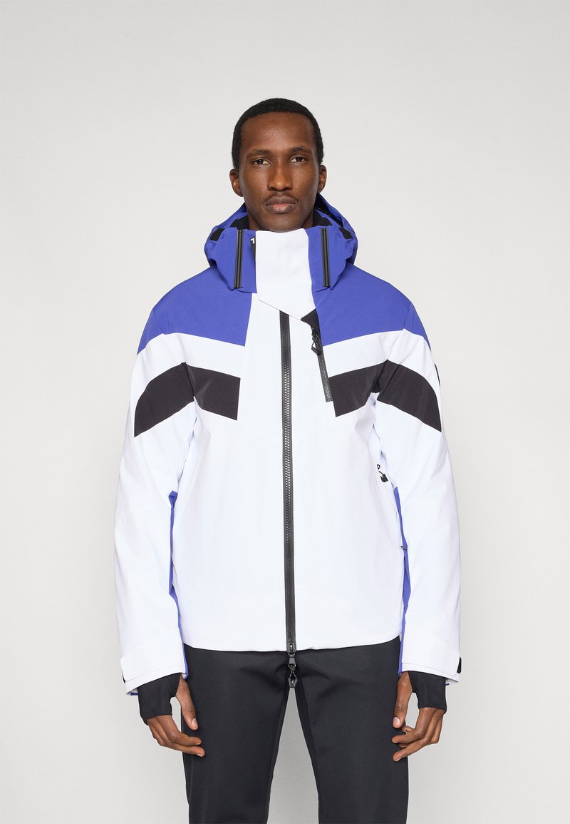 Biela a modrá lyžiarska bunda s čiernymi akcentmi. Má vysoký golier, nastaviteľnú kapucňu a zips vpredu. Materiál pôsobí vodoodpudivo.