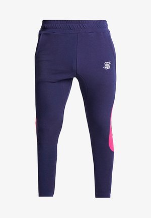 Joggeurs slim bleu marine avec taille élastique, poches latérales, panneaux roses sur les mollets et logo blanc brodé sur la cuisse gauche.