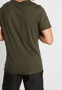 Olivově zelené tričko s krátkým rukávem z měkké látky, s kulatým výstřihem a jednoduchým designem bez viditelných vzorů či ozdob.