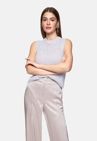 Helllila ärmelloses Stricktop mit strukturiertem Blattmuster, kombiniert mit hellrosa weitem Bein-Hosen, die aus einem sanften und glatten Stoff gefertigt sind.