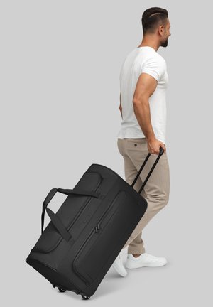 Sac de voyage noir à roulettes avec deux poignées, compartiments zippés et roulettes. Fabriqué en matériau durable, avec une surface lisse et texturée.