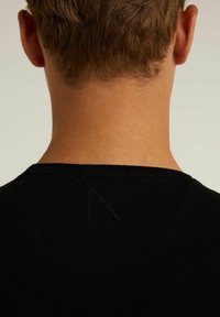Černé žebrované tričko s kulatým výstřihem, zobrazující zadní část krku, s malým, volným šitím poblíž límce.