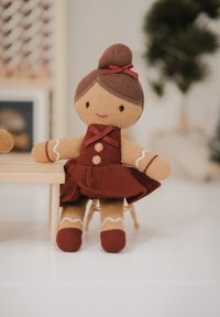Soft fabric doll with a brown bun, dressed in a burgundy dress with white trim, and two red bows. Features simple facial details.