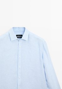 Camicia a maniche lunghe a righe blu chiaro con colletto classico, chiusura frontale con bottoni e taschino singolo. Realizzata in un morbido tessuto.