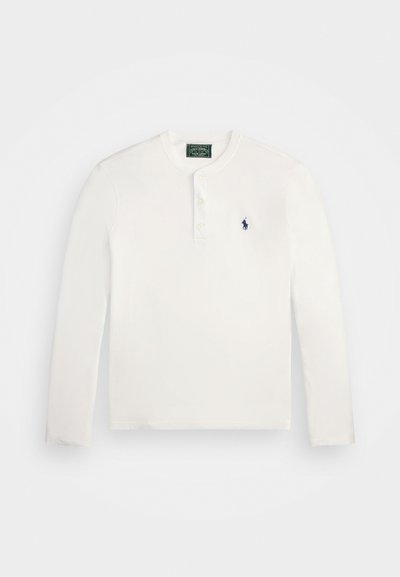 Λευκό βαμβακερό πουκάμισο με μακριά μανίκια και λαιμόκοψη henley, τρία κουμπιά και ένα μικρό μπλε κεντημένο λογότυπο στο στήθος.