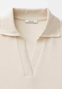 Beige poloshirt met een geribde kraag en V-hals ontwerp. Voorzien van een label met het opschrift "OPUS", een gladde textuur en een minimalistische stijl.