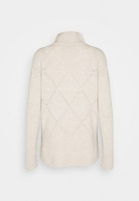 Cream knit sweater with a high collar, featuring a diamond pattern and ribbed cuffs. Made from soft material, textured with open stitches.