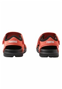 Pair of red and black open-back sandals with adjustable straps and "reima" branding on the heel straps, shown from the back.