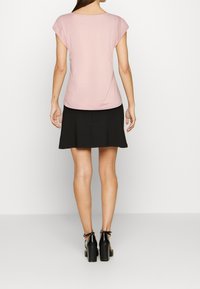 Rosa kortärmad topp med rundad halsringning, tillsammans med en svart utsvängd kjol. Klädseln har en mjuk yta och en enkel design.