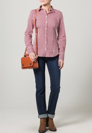 Rød og hvid ternet skjorte med knaplukning, denim jeans, brune ankelstøvler og en lille brun taske med klap og to sølvspænder.