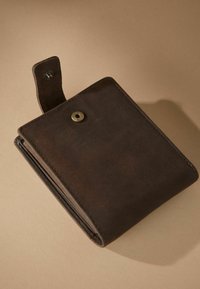 Brown leather wallet with a textured finish, featuring a metal snap closure and a removable strap detail. Compact, rectangular design.