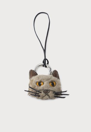 Llavero suave en forma de cara de gato gris con ojos amarillos, bigotes negros y orejas interiores marrones, unido a un lazo negro y un anillo plateado.
