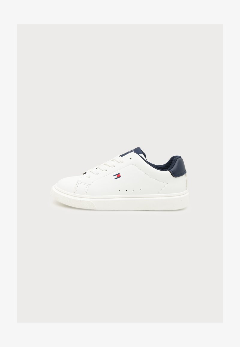 Λευκό low-top αθλητικό παπούτσι με σκούρο μπλε γιακά φτέρνας, κορδόνια και μικρό κόκκινο, λευκό και μπλε λογότυπο στο πλάι, σε απλό φωτεινό φόντο.