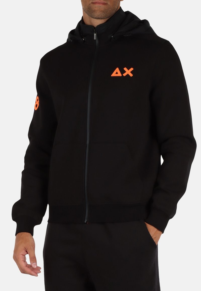 Felpa con zip nera dal design aderente, con un logo arancione sul petto e un accento sul braccio. Realizzata in tessuto morbido.