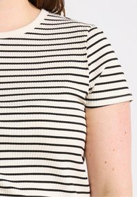 Hvid ribbet t-shirt med vandrette sorte striber, korte ærmer og rund hals. Stoffet har en struktureret overflade.