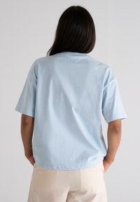 Light blue cotton t-shirt with a relaxed fit, short sleeves, rounded neckline, and a smooth texture. Visible stitching along the edges.