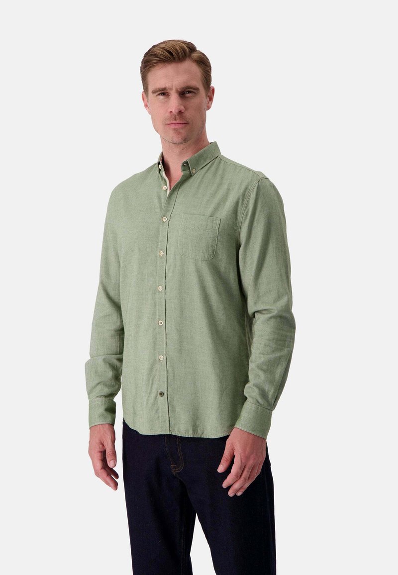 Camicia verde chiaro con bottoni, realizzata in tessuto testurizzato, dotata di una tasca sul petto, maniche lunghe e bottoni in contrasto. Indossata con jeans scuri.